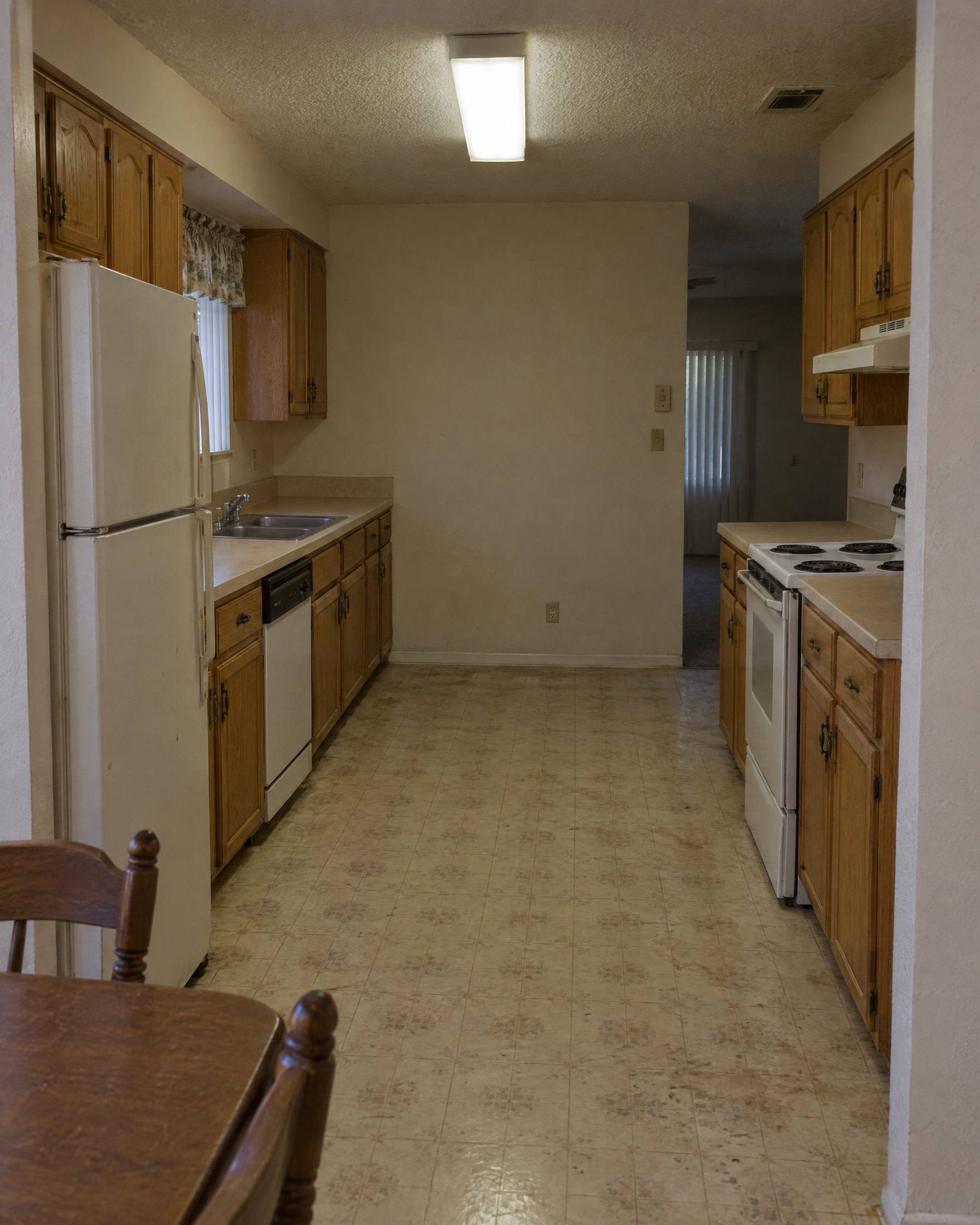 The same kitchen before: honey oak cabinets, laminate counters and a fluorescent light